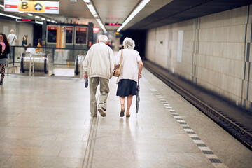 Older happy couple walking together on subway