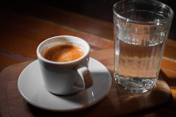 Fresh espresso with cup of water on table on black background