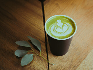 Matcha tea in paper cup on table, latte-art