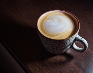 Cappuccino in cup on wood table, with latte-art
