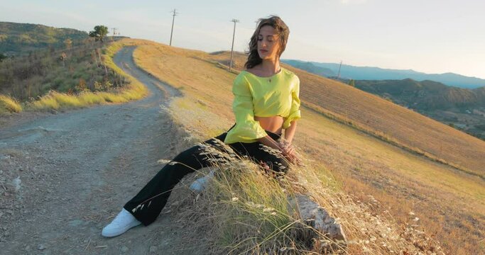 Ragazza si diverte in una strada di campagna, maglia giallo e pantaloni nero.