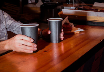 Two coffee latte in hands barista, with bun on background
