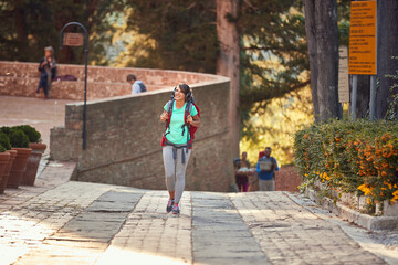 Fototapeta na wymiar female enjoying in active sightseeing in italy, walking with backpack, head up, smiling