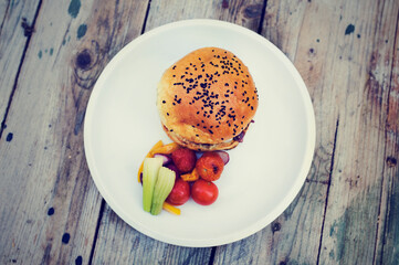 Homade vegetarian hamburger with chees, onion sauce, grilled vegetables and homade pastry on old vintage wood table