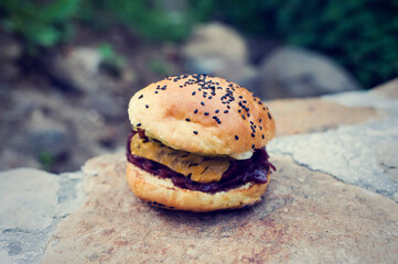 Beef hamburger with chees, onion sauce and homade pastry outdoor on stone wall