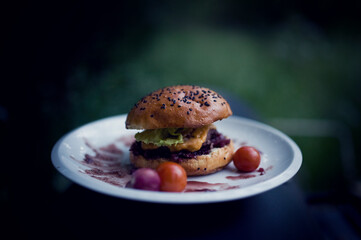 Beef hamburger with chees, onion sauce, vegetables and homade pastry. Summer outdoor kittchen.
