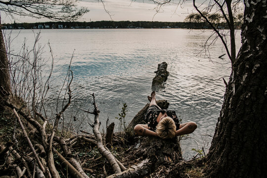 Europe, Germany, Berlin, Mueggelheim, Grosse Krampe, woman relaxing on a tree in the lake.