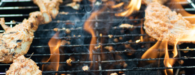 Feuer brennt im Grill und Fleisch wird auf dem Grill gekocht
