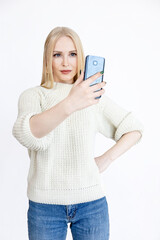 young blonde girl with a calm face looks in a smartphone on a white background