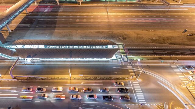 Aerial top view to Sheikh Zayed road near Dubai Marina and JLT night timelapse, Dubai. Traffic on highway, footbridge between metro and tram station. United Arab Emirates