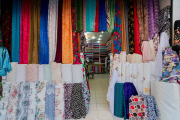 clothes for sale. clothes in shop, Rolls of fabric and textiles for sale stacked on shelves in shop, View of cloth rolls of different colors and patterns on shelves in fabric store