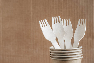 Wooden forks and paper cups on kraft paper background. Eco friendly disposable tableware. Also used in fast food, restaurants, takeaways, picnics. Copy, empty space for text