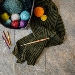 multi-colored balls of thread and a nearby knitted scarf
