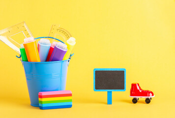 A metal bucket with highlighter marker pen and school ruler, red roller and small blackboard on a...