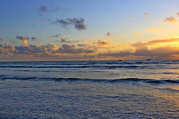 Fototapeta na wymiar Guarajuba beach, Bahia, Brazil. Sunrise over the sea. Orange sky with clouds and small waves in the sea.