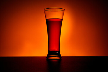 Tall glass of cold tea on warm yellow background. Fresh summer beverage.