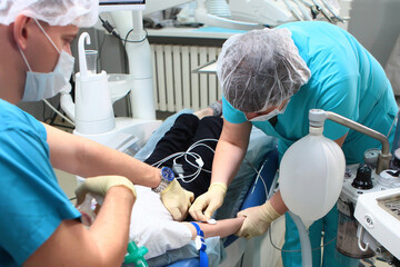 The anesthesiologist and his assistant put the child under anesthesia. Preparing the child for...