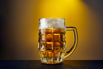 Cold craft light Beer in a mug with drops on a dark table. Pint of Beer on yellow color background.