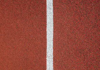 Red rubber running track texture close up. White divider line in the center.
