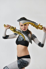 beautiful brunette girl in a robot suit posing with golden swords on a white background