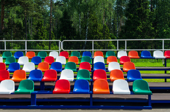 Colorful empty stands in a stadium. Red, blue, green, white and orange plastic seats.
