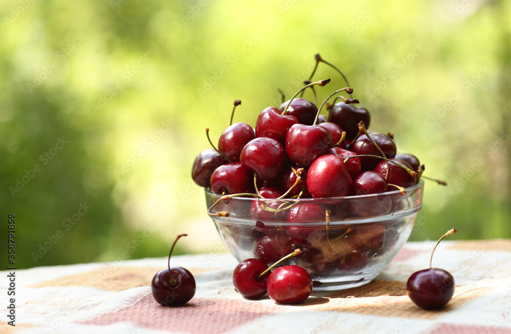 Wall mural healthy breakfast - sweet cherry in bowl close up photo on green grass background