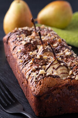 Delicious chocolate cake with pears and walnuts on dark background