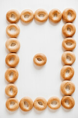 Drying or mini round bagels in the form of a frame on a white wooden background. Top view. Copy, empty space for text