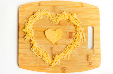 Cheese in the shape of a heart on a wooden Board. Grated cheese in the shape of a heart. Hard cheese.