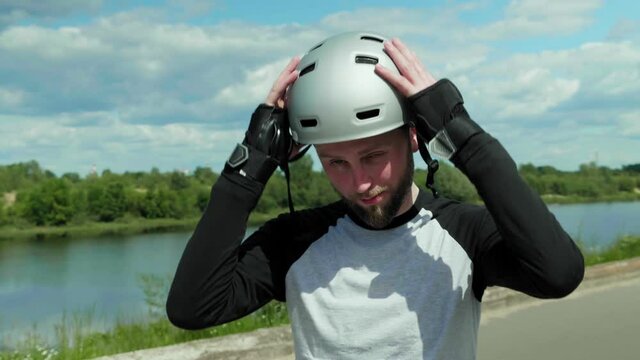 Portrait of a man outdoors taking off his safety helmet and smiling. Medium shot