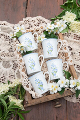 Set of coffee cups with blue flowers - in the background lace, flowers and wooden desk