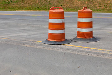 Two traffic safety barrels on an asphalt street, road construction barriers, horizontal aspect