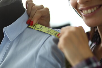 Smiling female designer taking measurements on a mannequin