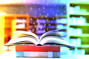 Fototapeta premium Open book on the table and English alphabet Floating above the book in the library and blur bookshelf background.