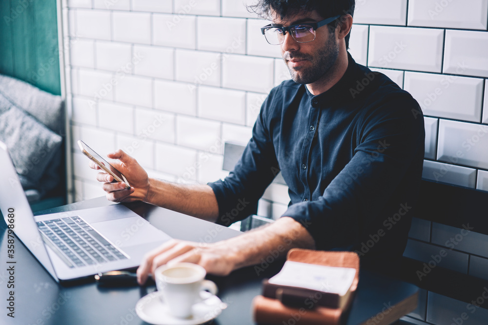 Poster skilled male owner of coffee shop checking financial account on netbook device.businessman in eyegla