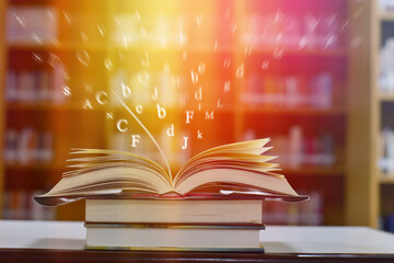 Open book on the table and English alphabet Floating above the book in the library and blur bookshelf background.