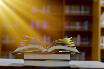 Naklejka premium Open Book on wood table and blurred bookshelf in the library, education background, back to school concept.