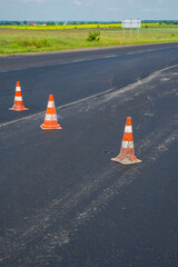 Traffic cones on the new asphalt. Road repair. Danger warning. Copy space. Vertical image.