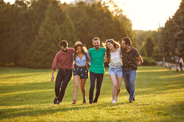 Group of friends hugging during their walk in countryside on summer day. Cheerful people enjoying their weekend outside