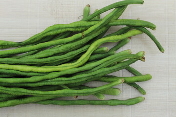 Green organic beans display on white texture surface. 