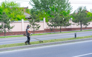 Naklejka premium People in a protective mask mow the grass with a lawn mower.