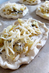 Focaccia with onions, herbs and cheese, garnished with poppy seeds before baking