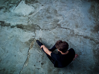 man sitting on the floor reflecting in life - Contemplating the Void - solitary man - introvert guy - Cracked ground