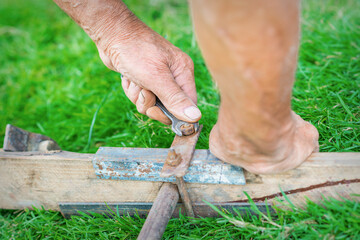 hand of an elderly man twisting the nut with a wrench outdoors. Repair by wrench.