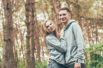 Fototapeta premium couple in identical sweatshirts in the forest, portrait of a couple in the forest