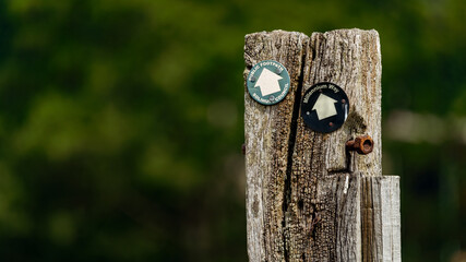 Walking path directional markers on an old wooden post for UK countryside right of way paths
