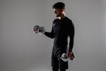 Muscular man doing exercises with dumbbells over white background. Fitness exercises with dumbbells...
