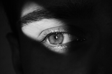 man hiding in the dark looking through a crack - social phobia 