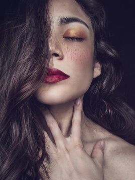 Intense beautiful woman  with freckles and hand on neck portrait - brown wavy hair - red lips