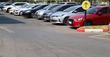 Closeup of front side of red car with  other cars parking in outdoor parking area in bright sunny day. 